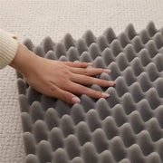 Close-up of hand pressing on gray egg crate foam cushioning for soft dog sofa bed orthopedic support
