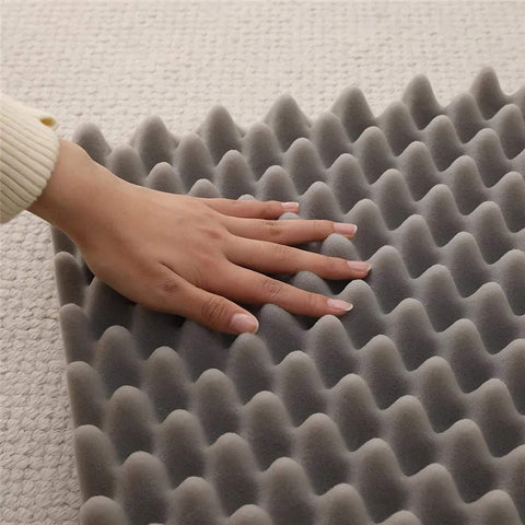Close-up of hand pressing on gray egg crate foam cushioning for soft dog sofa bed orthopedic support